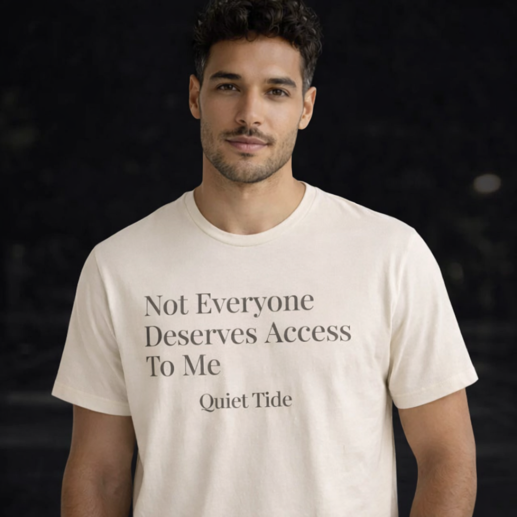 Man wearing Quiet Tide natural t-shirt with “Not Everyone Deserves Access To Me” text on front against dark background